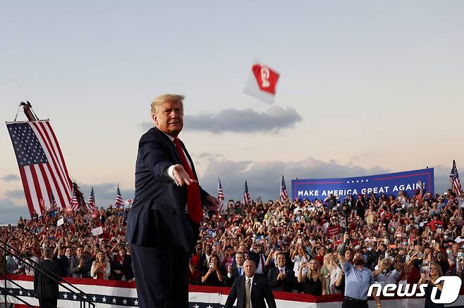 도널드 트럼프 미국 대통령이 12일(현지시간) 코로나 감염 열흘만에 음성판정을 받고 플로리다주 샌퍼드의 올랜도 샌퍼드 국제공항에서 열린 선거집회에 도착해 지지자들에게 마스크를 던지고 있다. © 로이터=뉴스1 © News1