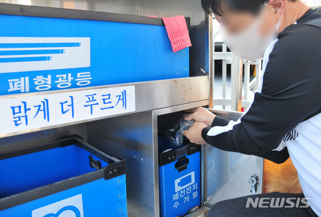 [광주=뉴시스] 김혜인 기자 = 주민이 24일 오전 광주 남구 주월동 모 아파트 분리수거장에서 폐건전지를 수거함에 버리고 있다. 2020.10.24. hyein0342@newsis.com