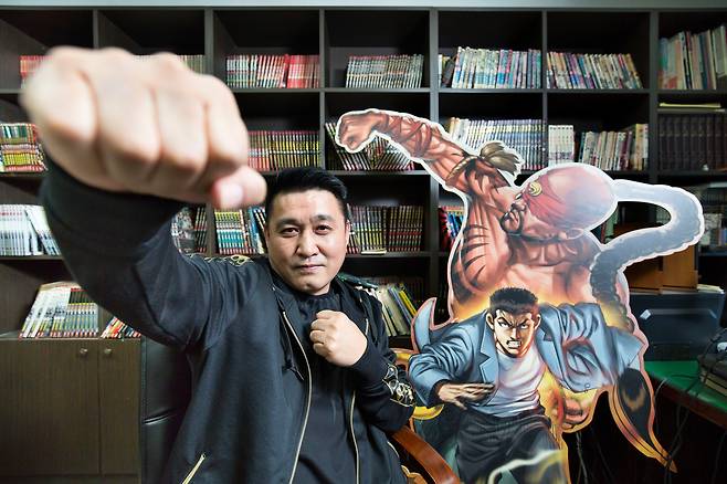 만화가 김성모가 2013년 연재한 ‘롤짱’의 캐릭터 리심을 따라 주먹을 뻗고 있다. 뒤로 보이는 책장에 자신이 낸 단행본이 꽂혀있다. 그는 “지금까지 타이틀 400여개 , 단행본 2200개가 나왔다”고 했다. / 한준호 영상미디어 기자