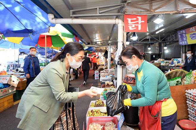 은수미 성남시장(왼쪽)이 전통시장에서 상남사랑상품권(지역회폐)으로 물건값을 치르고 있다. 성남시 제공