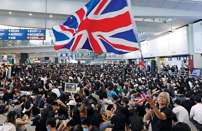 범죄인 인도법에 반대하는 홍콩 시위대 1000여명이 작년 8월 홍콩 국제공항에서 시위를 벌이고 있다. 한 시위 참가자가 중국을 거부한다는 의미로 영국 국기를 흔들고 있다. /AP 연합뉴스