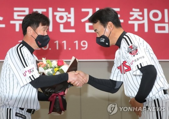 류지현 감독이 김동수 수석코치로 부터 축하 꽃다발을 받고 악수를 나누고 있다.