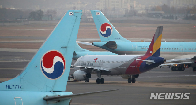 [서울=뉴시스] 조수정 기자 = 대한항공이 아시아나항공을 인수하기로 한 16일 서울 강서구 김포국제공항 국내선청사 전망대에서 바라본 계류장에 대한항공 여객기 사이로 아시아나항공 여객기가 이동하고 있다. 2020.11.16.  chocrystal@newsis.com