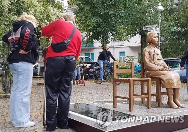 올해 9월 25일(현지시간) 독일 수도 베를린에 설치된 '평화의 소녀상'에 쓰인 비문을 지나가던 시민들이 읽고 있다. [연합뉴스 자료사진]