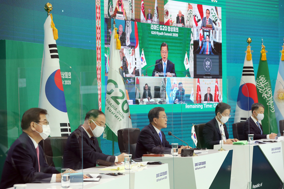 Korean President Moon Jae-in, center, flanked by aides, speaks during a virtual summit of the Group of 20 (G-20) leaders of major economies at the Blue House on Saturday. [JOINT PRESS CORPS]