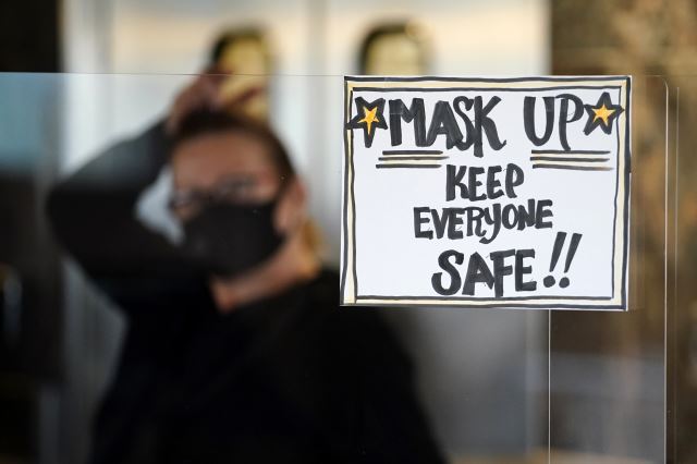 심각한 코로나19 상황 속에 '마스크를 쓰자'는 문구를 달아놓은 미국의 상점 직원. AP연합뉴스