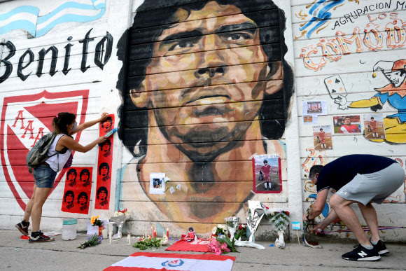 아르헨티나의 수도 부에노스아이레스의 ‘마라도나 스타디움’ 벽에 그려진 초상화 앞에서 마라도나를 애도하고 있는 시민들.