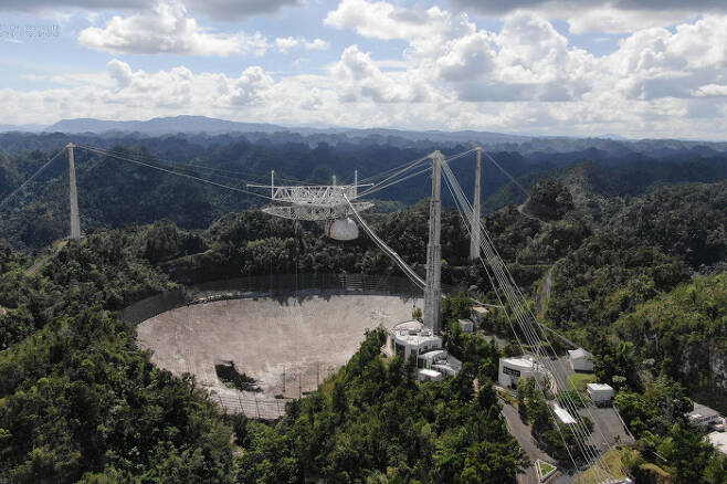 이달 초 일어난 철제 케이블 추락사고로 지름 305m짜리 접시 안테나에 큰 구멍이 뚫린 푸에르토리코에 있는 아레시보 전파망원경. 미국 국립과학재단(NSF)은 망원경의 전체적인 내구성이 약해졌다며 수리 대신 전면 해체 결정을 내렸다.  미국 센트럴플로리다대 제공