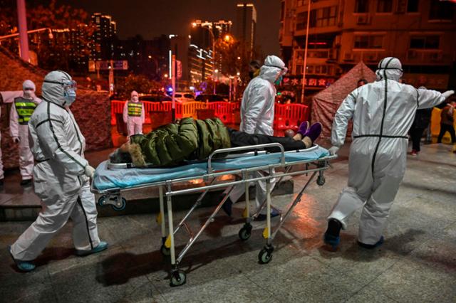 지난 1월 25일 중국 후베이성 우한에서 코로나19가 확산하는 가운데 의료진이 환자를 병원으로 옮기고 있다. 우한=AFP 연합뉴스