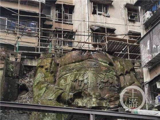 중국 충칭의 한 주택 단지에서 아파트를 떠받치고 있는 머리 없는 대형 석각이 발견돼 커다란 화제가 되고 있다. 불상이냐 아니냐는 논쟁도 뜨겁다. [중국 남방도시보망 캡처]
