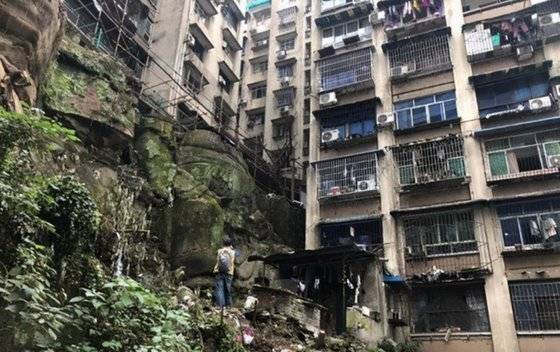 중국 충칭의 난안구에서 발견된 대형 석각은 높이 9m 정도로 머리 부분으로 9층 아파트 건물을 이고 있다. [중국 텅쉰망 캡처]