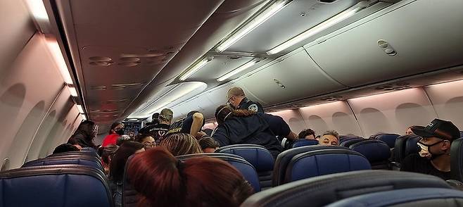 코로나19 감염사실을 숨긴 채 탑승했다가 비행기에서 의식을 잃은 남성을 돕기 위해 승무원과 승객들이 나선 모습