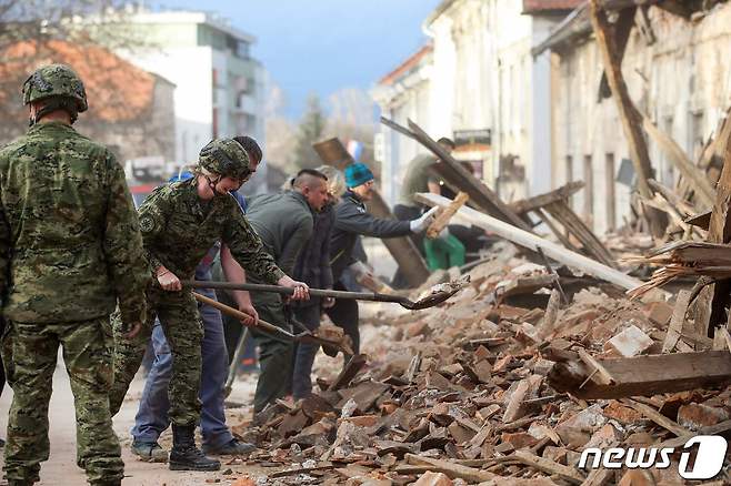 크로아티아 페트리냐에서 군인과 시민들이 지진으로 인해 붕괴된 잔해를 치우고 있다. © AFP=뉴스1