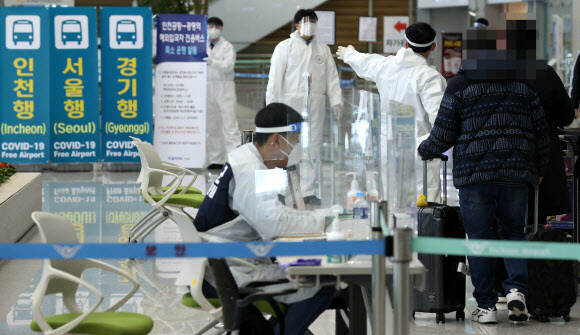 30일 오후 인천국제공항 제2여객터미널 입국장에서 일본 오사카발 항공편 입국자들이 방역 관계자들의 안내를 받고 있다. 연합뉴스