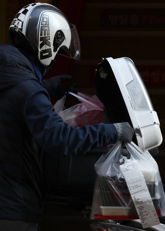 A delivery service worker carries packaged meals in Myeong-dong, one of the busiest shopping districts in Seoul, on Thursday, amid a surge in coronavirus cases. South Korea has imposed a nationwide ban on gatherings of five or more people as part of efforts to stem the spread of the coronavirus. (Yonhap)