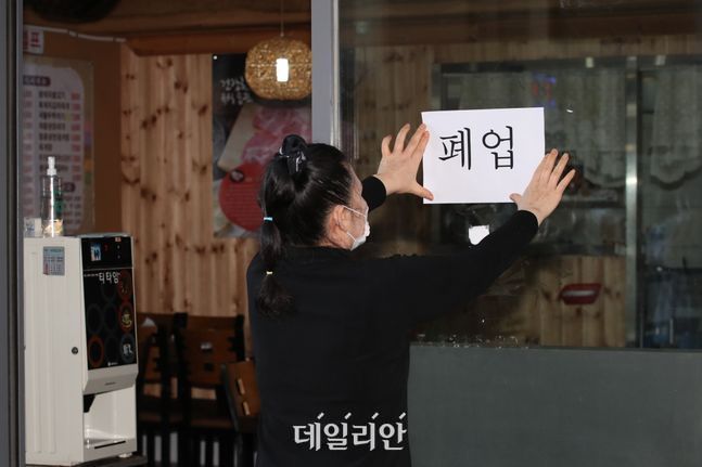 서울 동작구에서 식당을 운영하는 손원주 사장이 9월 18일 식당 문에 폐업이 적힌 종이를 붙이고 있다.ⓒ데일리안 류영주 기자