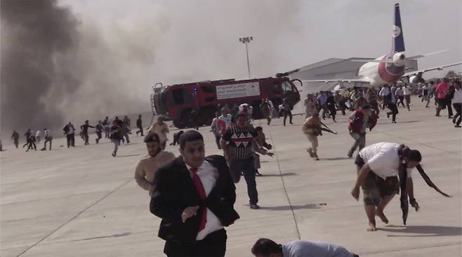 30일(현지시간) 예멘 남부 아덴의 공항에서 큰 폭발이 일어난 직후 사람들이 달아나고 있다. AP|연합뉴스