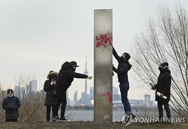 1일(현지시간) 캐나다 토론토 험버베이 공원에서 시민들이 금속기둥을 만지고 있다.