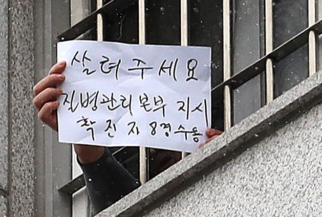 지난해 12월29일 대규모 집단감염이 발생한 서울 동부구치소에서 한 수용자가 '살려주세요'라고 쓴 문구를 창밖으로 내보이고 있다. / 사진=뉴스1