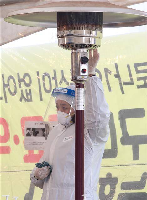 새해 첫 주말인 3일 서울 용산역 앞 코로나19 임시 선별검사소에서 의료진이 난로와 핫팩으로 손을 녹이며 추위와 싸우고 있다. 서울시는 임시 선별검사소를 오는 17일까지 연장 운영한다.뉴스1
