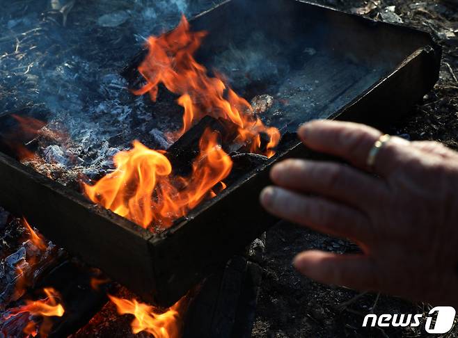 전북 전주시 남부시장에서 한 상인이 모닥불을 쬐며 추위를 녹이고 있다. © News1 유경석 기자