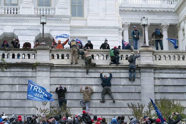 도널드 트럼프 미국 대통령 지지 시위대가 6일(현지시간) 워싱턴DC 연방의회 의사당 서쪽 벽을 기어오르고 있다. AP 연합뉴스