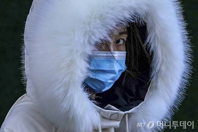 [베이징=AP/뉴시스]16일 출근 시간 중국 베이징의 한 지하철역에서 코로나19 확산 예방을 위해 마스크를 쓴 여성이 추운 듯 두터운 방한복을 입고 출근길에 나서고 있다. 2020.12.16.