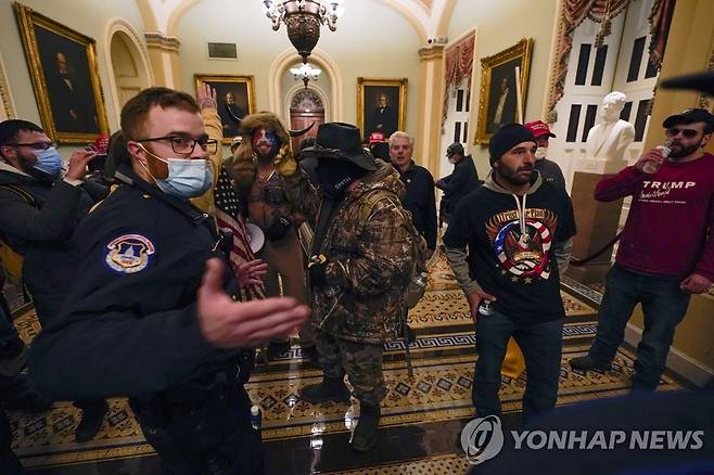 미 연방 의회 의사당에 진입한 시위대와 이를 감시하는 경찰관 [AP=연합뉴스]