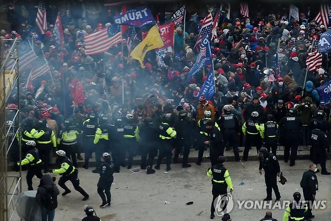 미 의사당에서 트럼프 지지 시위대와 몸싸움하는 경찰 (워싱턴 AFP=연합뉴스) 미국 워싱턴DC 국회의사당 경내 원형 홀 밖에서 6일(현지시간) 경찰이 도널드 트럼프 대통령 지지 시위대와 몸싸움을 벌이고 있다. 상ㆍ하원은 이날 합동회의를 개최해 조 바이든 대통령 당선인의 승리를 인증할 예정이었으나 시위대의 의사당 난입 사태로 회의가 전격 중단됐다. sungok@yna.co.kr