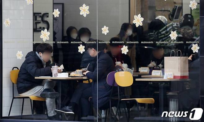 (서울=뉴스1) 김진환 기자 = 정부가 국내 신종 코로나바이러스 감염증(코로나19) '3차 대유행' 확산세를 꺾기 위해 현재 사회적 거리두기(수도권 2.5단계·비수도권 2단계) 기준을 2주 더 유지하기로 했다. 특히 그동안 수도권에서만 적용해왔던 '5인 이상 사적 모임' 금지 조처를 전국으로 확대한다.   이에 따라 직장 동료들이 함께 식당에서 점심·저녁 식사를 하는 것을 포함한 회식, 동창회, 동호회, 계모임, 집들이, 신년회, 온라인 카페 정기 모임 등 일체 모임들은 5인 이상으로는 할 수 없다. 이 방역 수칙을 위반하면 운영자에게는 300만원 이하, 이용자에게는 10만원 이하의 과태료가 각각 부과된다.   사진은 4일 오후 서울 중구 한 패스트푸드점을 이용하는 시민들. 2021.1.4/뉴스1