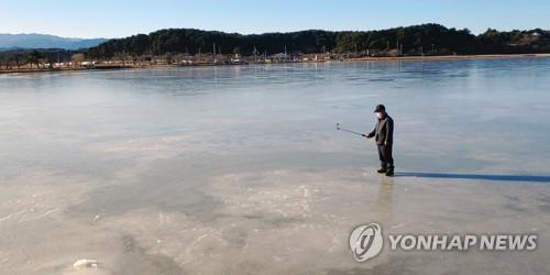 (강릉=연합뉴스) 이해용 기자 = 8일 북극한파에 얼어붙은 강원 강릉시 경포호에서 한 시민이 기념사진을 찍고 있다