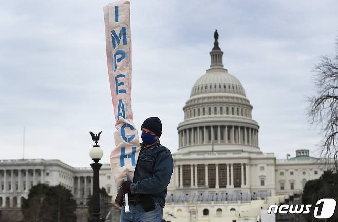 8일(현지시간) 한 남성이 미국 워싱턴DC 연방의회 의사당 근처에서 '탄핵'이라고 적힌 플래카드를 들고 있다. © AFP=뉴스1
