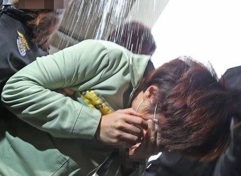 울산에서 지난 2013년 서현이 학대 사망 사건이 발생한 뒤 재판에 출두한 계모가 재판이 끝난 후 호송버스에 오르는 순간 '하늘로 소풍간 아이를 위한 모임' 카페 회원이 뿌린 물을 맞고 있다. 연합뉴스