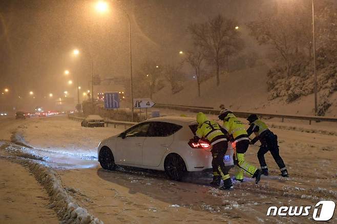 지난 9일(현지시간) 내린 스페인 대폭설로 인해 한 차량이 움직이기 힘들어지자 경찰이 나서 밀어주고 있다. © AFP=뉴스1 © News1 박재우 기자