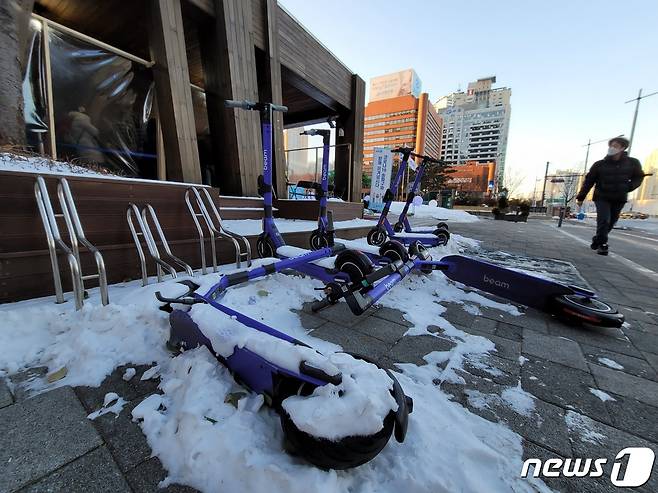 9일 오후 서울 송파구 송파보건소 앞에 공유 전동킥보드가 눈에 파묻힌 채 누워 있다. 눈이 말끔하게 정리된 인도와 상반된 모습이다. © 뉴스1 이밝음 기자