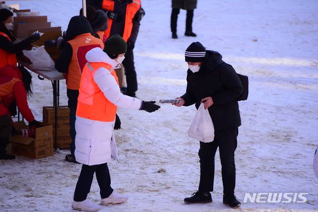 [서울=뉴시스]지난 8일 명동밥집이 마련된 옛 계성여중고 운동장에서 명동밥집 관계자가 노숙인에게 도시락을 나눠주고 있다.(사진=천주교 서울대교구 제공)2021.01.12 photo@newsis.com