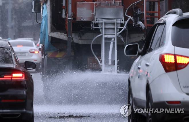 퇴근길 대란 없으려면 (서울=연합뉴스) 홍해인 기자 = 오후 들어 서울 지역에 눈이 내리기 시작한 12일 오후 서울 종로구 일대 도로에서 제설작업차량이 염화칼슘을 살포하며 이동하고 있다. 2021.1.12 hihong@yna.co.kr