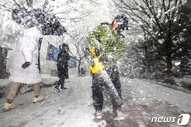 12일 오후 경기도 고양시 호수공원에서 관계자들이 갑자기 내리는 폭설에 제설작업을 하고 있다. 이날 기상청은 낮부터 추위가 풀리며 서울·경기 지방에 눈이 내릴 것으로 예보했다. 2021.1.12/뉴스1 © News1 성동훈 기자