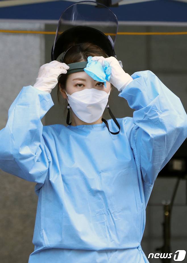 전주지역에 연일 신종 코로나바이러스 감염증(코로나19) 확진자 발생과 폭염이 이어지고 있는 지난해 8월20일 전북 전주시 화산체육관에 마련된 코로나19 선별진료소에서 한 의료진이 더위로 가득한 페이스 마스크를 벗으며 더위를 식히고 있다. 2020.8.20/뉴스1 © News1 유경석 기자