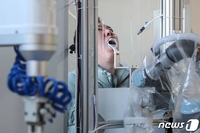 13일 중국 랴오닝성 선양시에서 로봇 팔을 이용한 코로나19 진단검사용 검체 채취가 이뤄지고 있다. © AFP=뉴스1