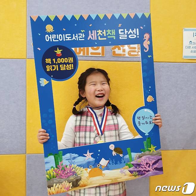 '세상을 바꿀 천 권의 책' 1호 달성자 한소윤양이 메달을 목에 걸고 환하게 웃고 있다.(이천시 제공) /© News1