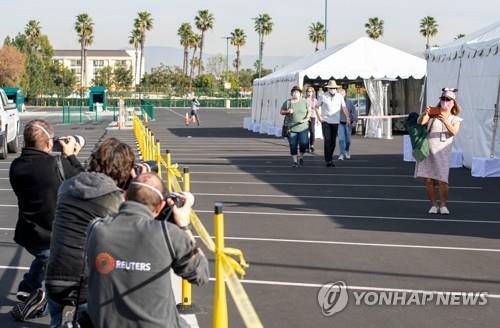 13일(현지시간) 미 캘리포니아 애너하임의 디즈니랜드에 마련된 코로나19 백신 접종소에서 백신을 맞고 나오는 사람을 기자들이 촬영하고 있다. /AFP연합뉴스