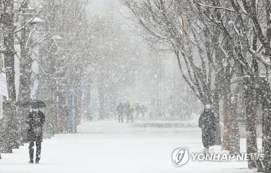 눈이 내리는 18일 오전 서울 광화문광장 인근에서 시민들이 눈을 맞으며 걸어가고 있다. 연합뉴스