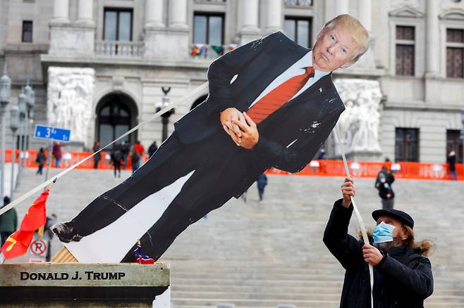 도널드 트럼프 미국 대통령을 비판하는 시위대 중 한 명이 17일(현지시간) 펜실베니아주 해리스버그 의사당 앞에서 트럼프 대통령의 모형을 끌어내리고 있다. 해리스버그|로이터연합뉴스