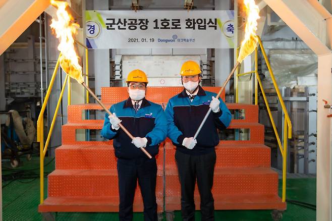 19일 테크팩솔루션 군산공장에서 열린 군산 1호 용해로 화입식에서김남정 동원그룹 부회장(오른쪽)과 서범원 테크팩솔루션 대표(왼쪽)가 용해로에불씨를 넣고 있다.