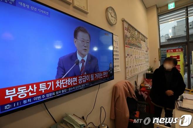 (서울=뉴스1) 이승배 기자 = 18일 오전 서울 시내의 한 공인중개사 사무소에서 부동산 업자가 문재인 대통령 신년 기자회견 생중계 방송을 지켜보고 있다.  청와대 춘추관에서 열린 이번 기자회견은 사회적 거리두기를 고려해 문재인 대통령 취임 후 처음으로 온·오프라인 화상 연결 방식으로 개최됐다. 2021.1.18/뉴스1