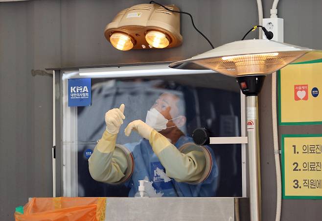 오는 20일 국내에서 신종 코로나바이러스 감염증(코로나19) 첫 확진자가 나온 지 꼭 1년째가 되는 가운데 19일 오후 서울광장에 마련된 임시 선별진료소에서 의료진이 난로로 손을 녹이고 있다. 연합뉴스