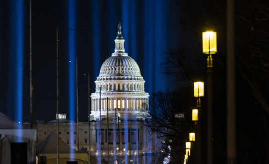 워싱턴DC의 연방 의사당 건물이 취임식에 참석하지 못하는 미국인들을 상징하는 20만여 개의 깃발로 구성된 공공 미술 전시 '깃발의 장(Field of Flags)'의 불빛을 받아 빛나고 있다.  EPA연합뉴스