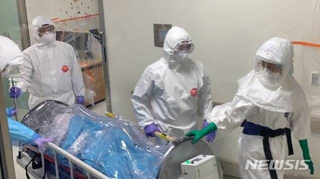 [제주=뉴시스] 제주대병원 의료진이 방호복과 멸균 가운, 호흡 보호구를 착용한 채 산모를 이동시키고 있다. (사진=제주대학교병원 제공)