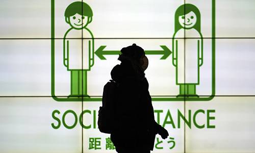 19일 마스크를 쓴 한 여성이 도쿄에 사회적 거리두기 안내문 앞을 걷고 있다. 도쿄=AP연합뉴스